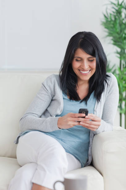 istock Woman relaxing on a couch while holding a phone 827646928