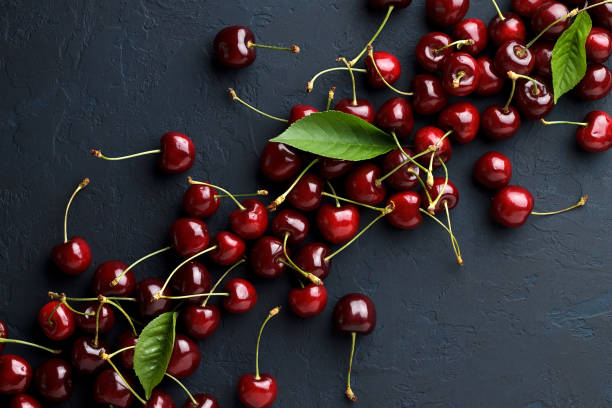 istock Berry backgrounds with fresh sweet cherries on dark blue stone. 827654178