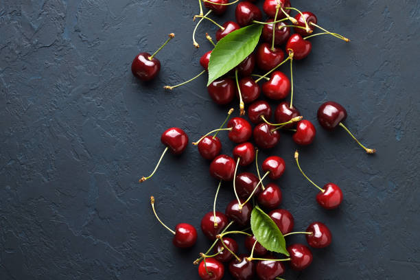 istock Berry backgrounds with fresh ripe sweet cherries on dark blue stone. 827654192