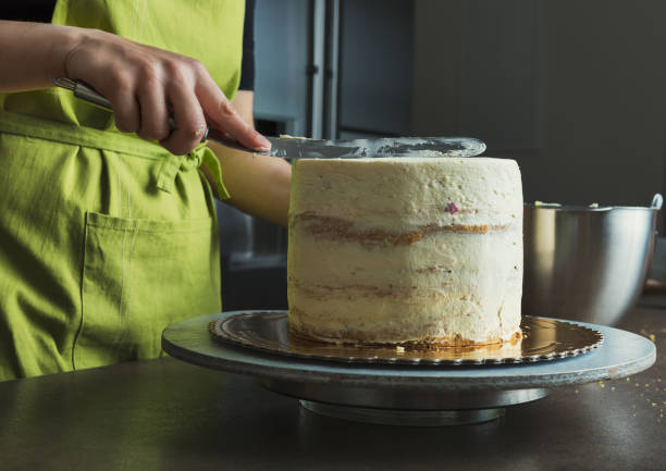 istock Woman decorating a delicious layered sponge cake with icing cream 827654408