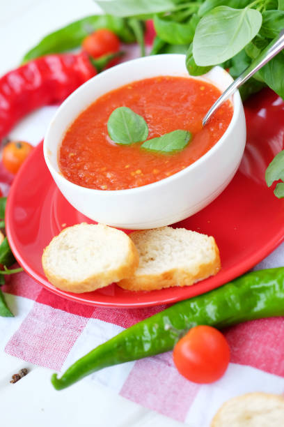 istock Cold summer tomato dish. Gaspacho soup with toast, cherry tomatoes, pepper, basil herbs. 827655500