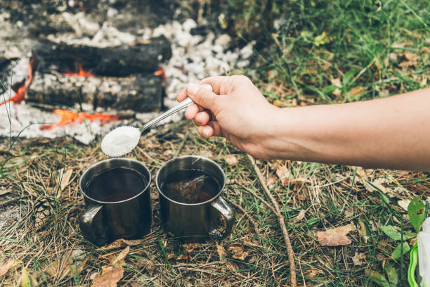 istock hand put suger in metal cup near bonfire 827658768