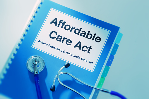 Concept still life of the U.S. Patient Protection and Affordable Care Act. The struggle to provide affordable healthcare to the public. Close-up of a medical stethoscope laying on top of a Affordable Care Act Manual Book.