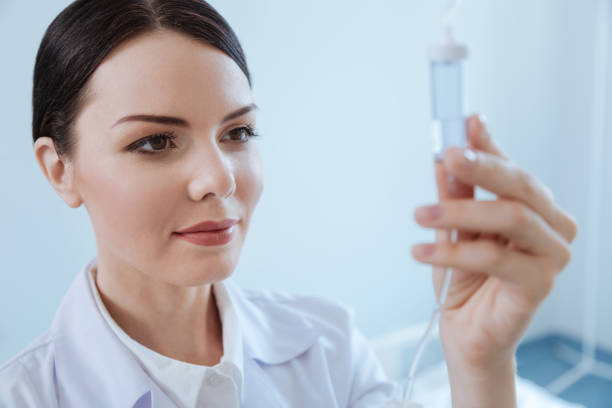 istock Pleasant professional nurse looking at the IV drip bottle 827663024
