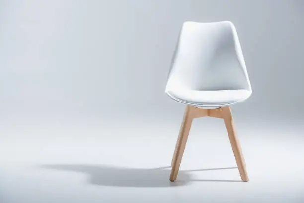 Photo of stylish chair with white top and light wooden legs standing on white