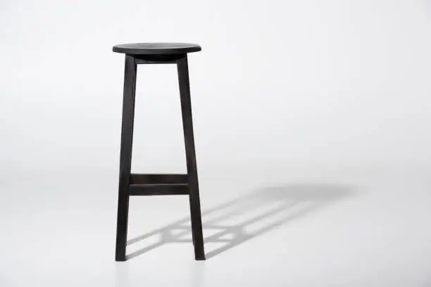 Studio shot of classic black tall wooden barstool standing on white