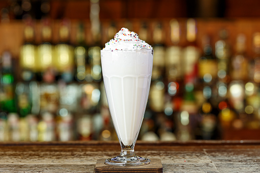 A tender milkshake with cream is on the bar in a cafe or restaurant, place for text