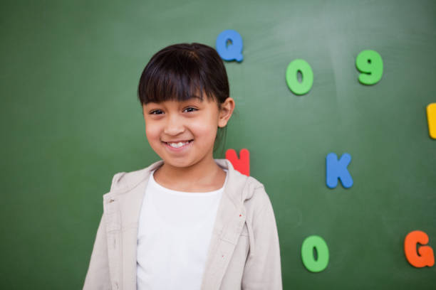 istock Happy schoolgirl posing in front of a blackboard 827680924