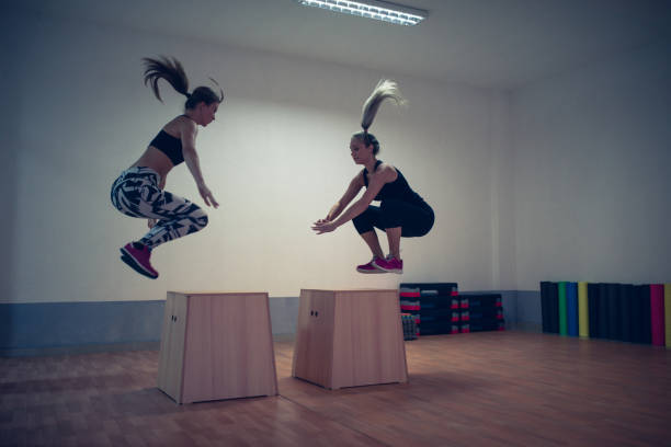 istock Young Female Athletes Doing Box Jump with Weights in Gym 827692130