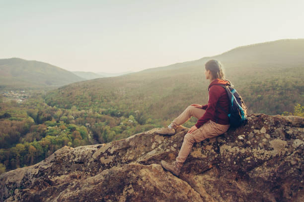 istock Traveler sitting on peak of rock. 827692280