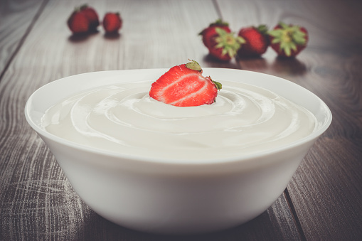 white bowl full of sour cream with strawberry on top
