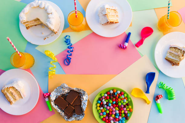 Cake, candy, chocolate, whistles, streamers, balloons, juice on holiday table. Concept of children's birthday party. View top.