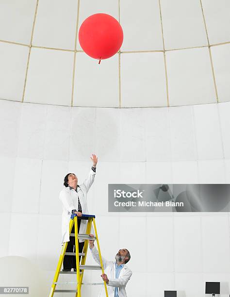 Scientist On Ladder Watches Balloon Float Away Stock Photo - Download Image Now - Scientist, Reaching, Full Length