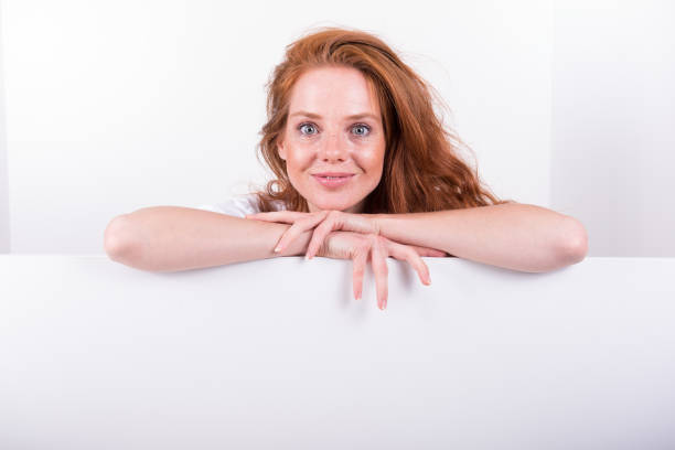 istock Beautiful red-haired woman holds a white board 827705798