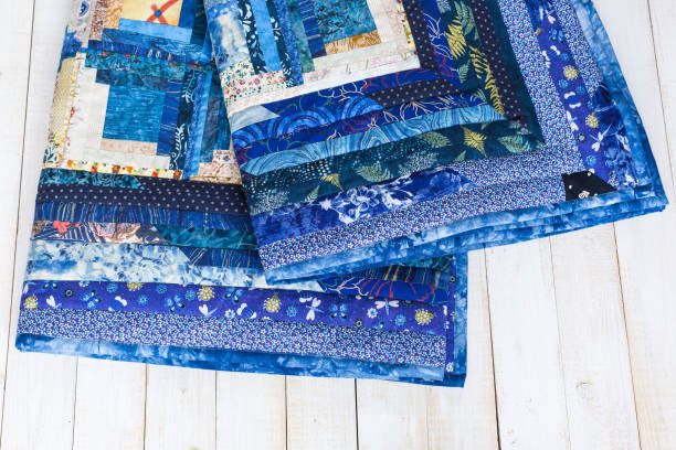 sewing, needlework, geometric, garment industry, cosiness, comfort concept - deep blue colored plaid sewed of textile squares with magnificent print on white wooden boards