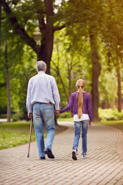 istock Girl and her disabled grandfather holding hands on walk 827709072