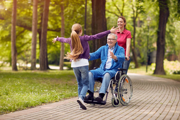 cheerful disabled grandfather in wheelchair welcoming his granddaughter cheerful disabled grandfather in wheelchair welcoming his happy granddaughter hospice photos stock pictures, royalty-free photos & images