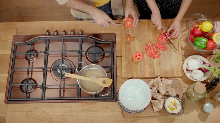 Man and woman cutting vegetables in the kitchen on a wooden board