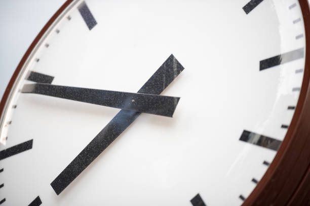 istock Retro clock with hour and minute hands close-up. Old white dial with black stripes instead of numbers. 827711054