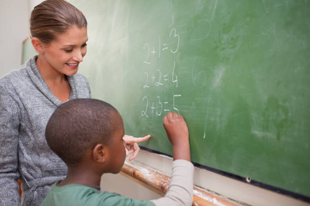 istock Cute teacher and a pupil making an addition 827711594