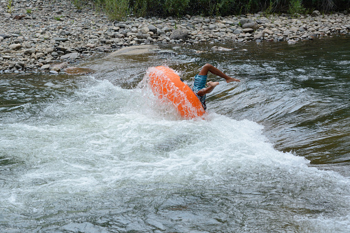 Inner tube float wipe out on white water rapid at Clear Creek White Water Park in Golden, Colorado