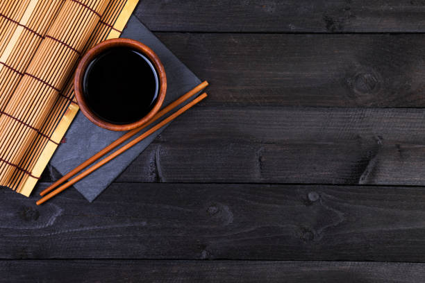 istock Bamboo mat and soy sauce on dark wooden table. Top view 827721444