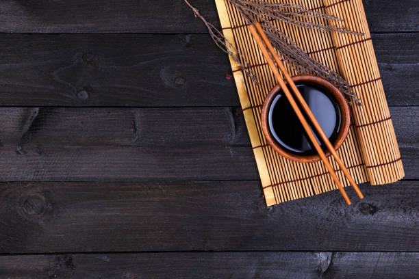 istock Bamboo mat and soy sauce on dark wooden table. Top view 827721460