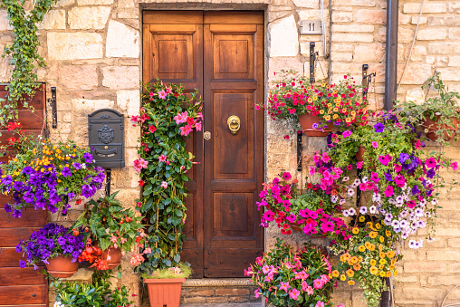Spello, Italy - May 27, 2017: Close up of a door of a residential building in Spello decorated ith colorful flowers.