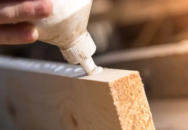 Carpenter. Glue on a piece of wood. Closeup.