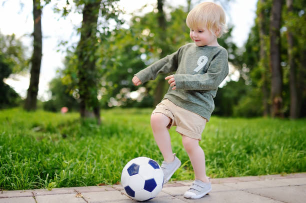istock Little boy having fun playing a soccer game on sunny summer day 827739562