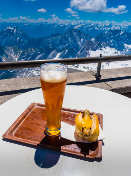 hot dog and german beer with view of alps mountain range on Zugspitze mountain , Germany stock photo