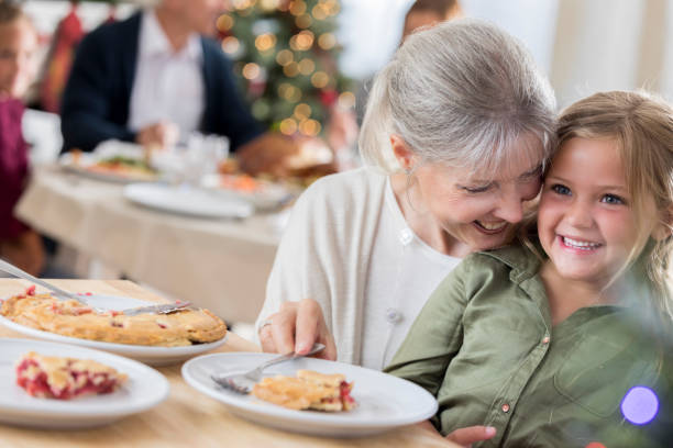 la bambina si diverte a mangiare la torta con la nonna durante il pranzo di natale - adult senior adult traditional culture usa foto e immagini stock