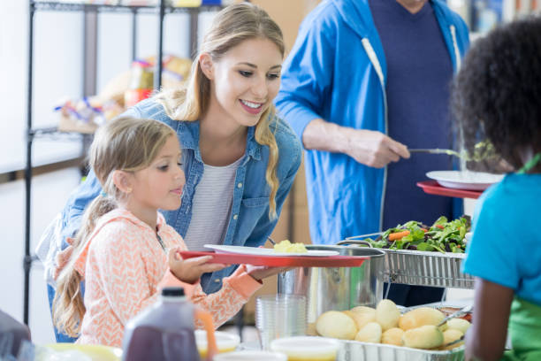 istock Mom and daughter receive meal in soup kitchen 827751020