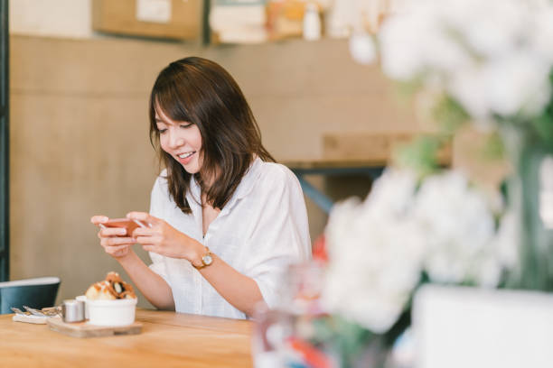Beautiful Asian girl taking photo of sweet desserts at coffee shop, using smartphone camera, posting on social media. Food photograph hobby, casual relax lifestyle, modern social network habit concept Beautiful Asian girl taking photo of sweet desserts at coffee shop, using smartphone camera, posting on social media. Food photograph hobby, casual relax lifestyle, modern social network habit concept japanese girlfriends stock pictures, royalty-free photos & images