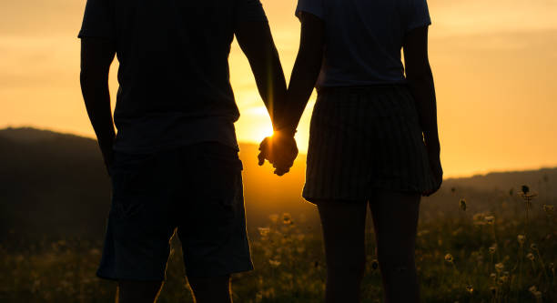 istock Couple holding hands and watching the sunset, silhouette 827757896