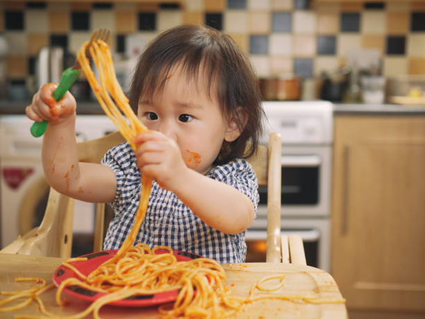 istock baby girl eating messy spaghetti 827760944