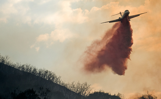 A firefighting airplane drops fire retardant on a wildfire in California.
