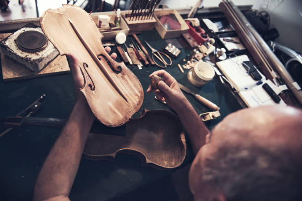 istock Senior skilled worker repairing violin 827780110