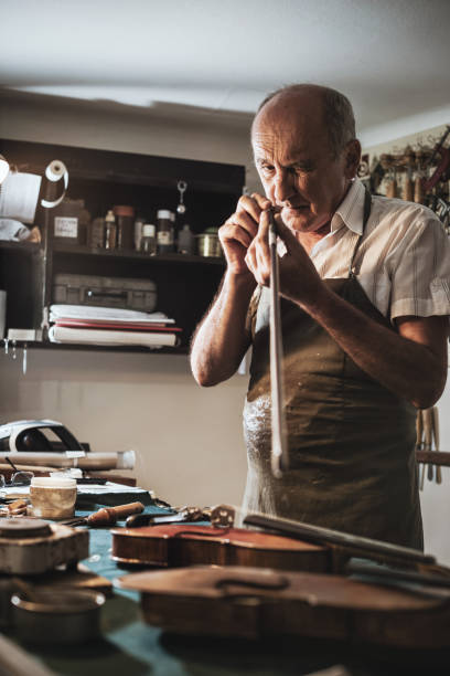 istock Senior craftsman in workshop with violins 827780228