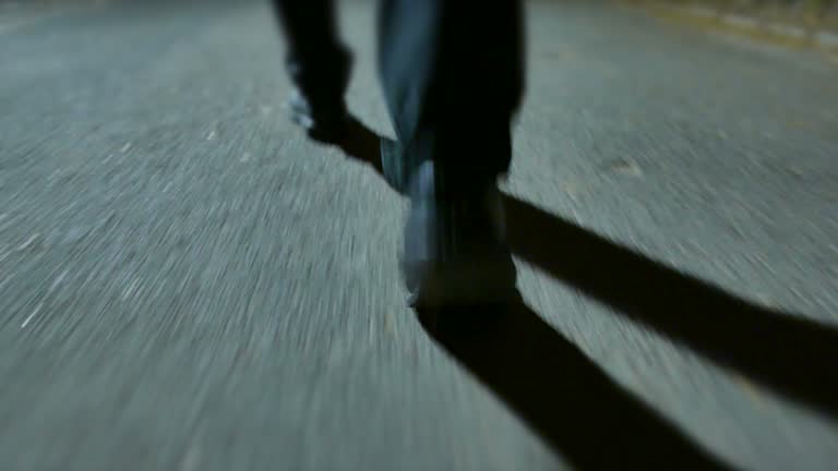 Young Caucasian Man Walking in the Park at Night. Taking a Walk in Casual Clothes. Dark Scenery with Large Shadows.