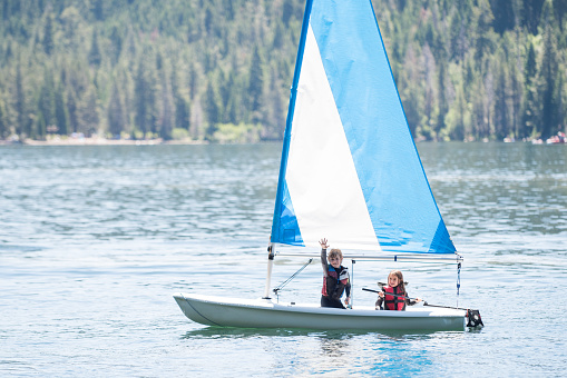 Children sailing alone on a beautiful mountain lake