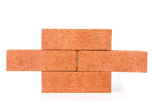 Four clay bricks building a wall against a white background