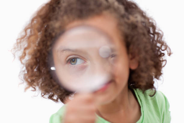 istock Smiling girl looking through a magnifying glass 827799420