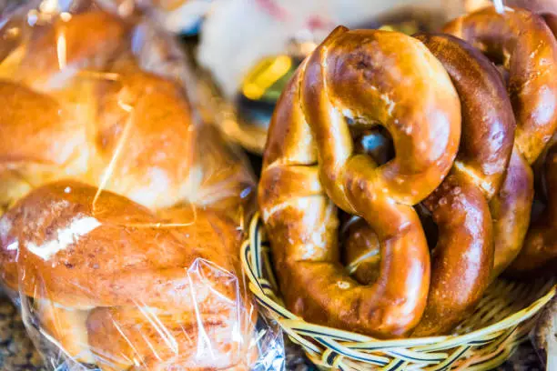 Closeup of fresh baked pretzels and challah bread in bakery baskets