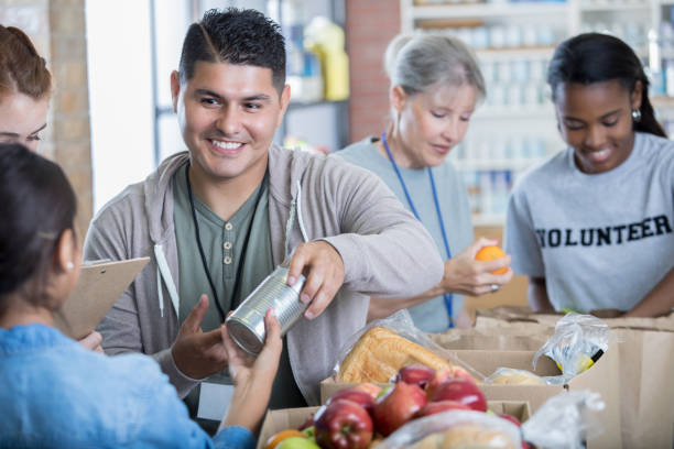 mid adult hispanic man volunteers during food drive - volunteer senior adult teenager occupation imagens e fotografias de stock