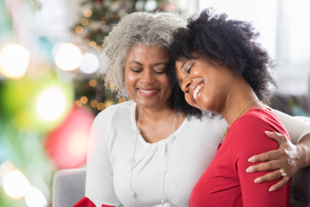 la chère mère aime passer du temps avec la fille adulte au moment de noël - senior adult child holding grandparent photos et images de collection