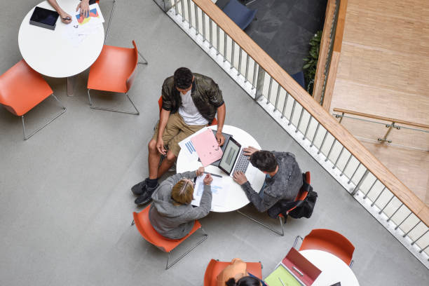 istock Small group of students working together, man using laptop, friend showing document 827810706