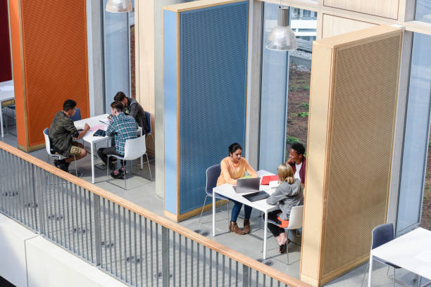 Groups of college students sitting in booths, discussing Multi racial students in modern college building working with laptops and books, high angle view common room stock pictures, royalty-free photos & images