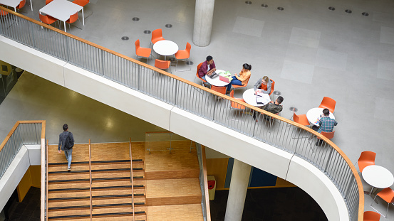 High angle view of modern college interior, furniture and steps, curved railings