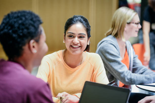 大学の教室で友人に聞いて陽気な若い女性笑顔 - england talking classroom education ストックフォトと画像